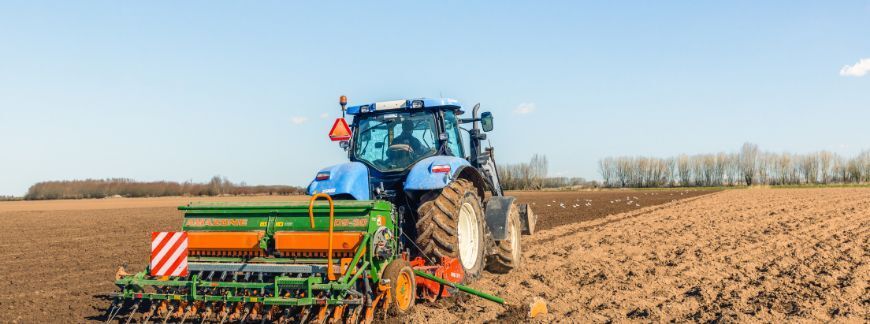 Ciągnik z broną i siewnikiem mechanicznym podczas przygotowania łoża siewnego i siewu zbóż na polu. Fot. Ruud Morijn Photographer - shutterstock.com