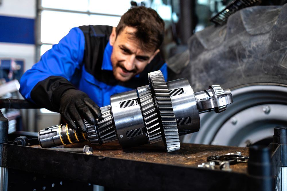 Mechanik sprawdzający podzesp&oacute;ł przekładni podczas serwisu ciągnika rolniczego i doboru części zamiennych